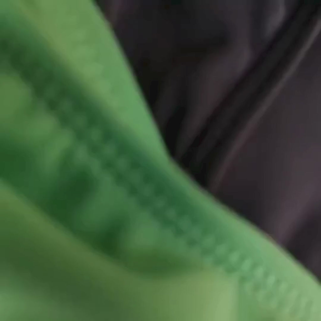 Macro close-up of green and black swim brief fabric, showing stitching and texture of quick-dry swimwear material.
