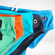 Close-up of assorted men's side eyelet swim briefs in multiple colors, highlighting eyelet detail and stretch fabric.