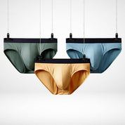 Three hanging Soft Modal Comfort Fit Men's Briefs in green, yellow, and blue, showcasing breathable fabric and stretch waistband.