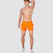 UrbanFit Basics Everyday Shorts in bright orange, modeled shirtless, offering vibrant style with stretch comfort and a snug fit.