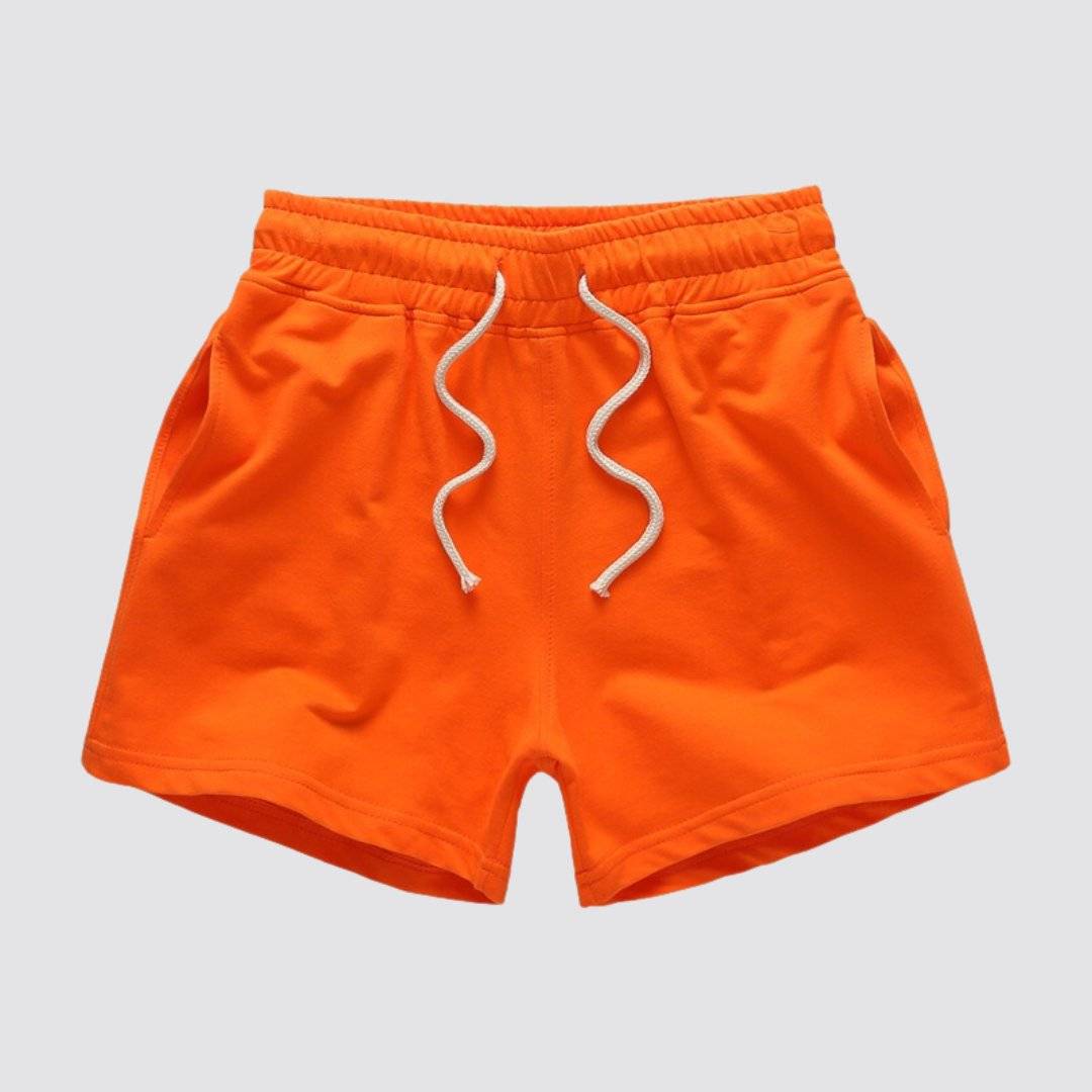 Flat lay of UrbanFit Basics Everyday Shorts in orange, with drawstring closure and side pockets, ideal for casual summer outfits.